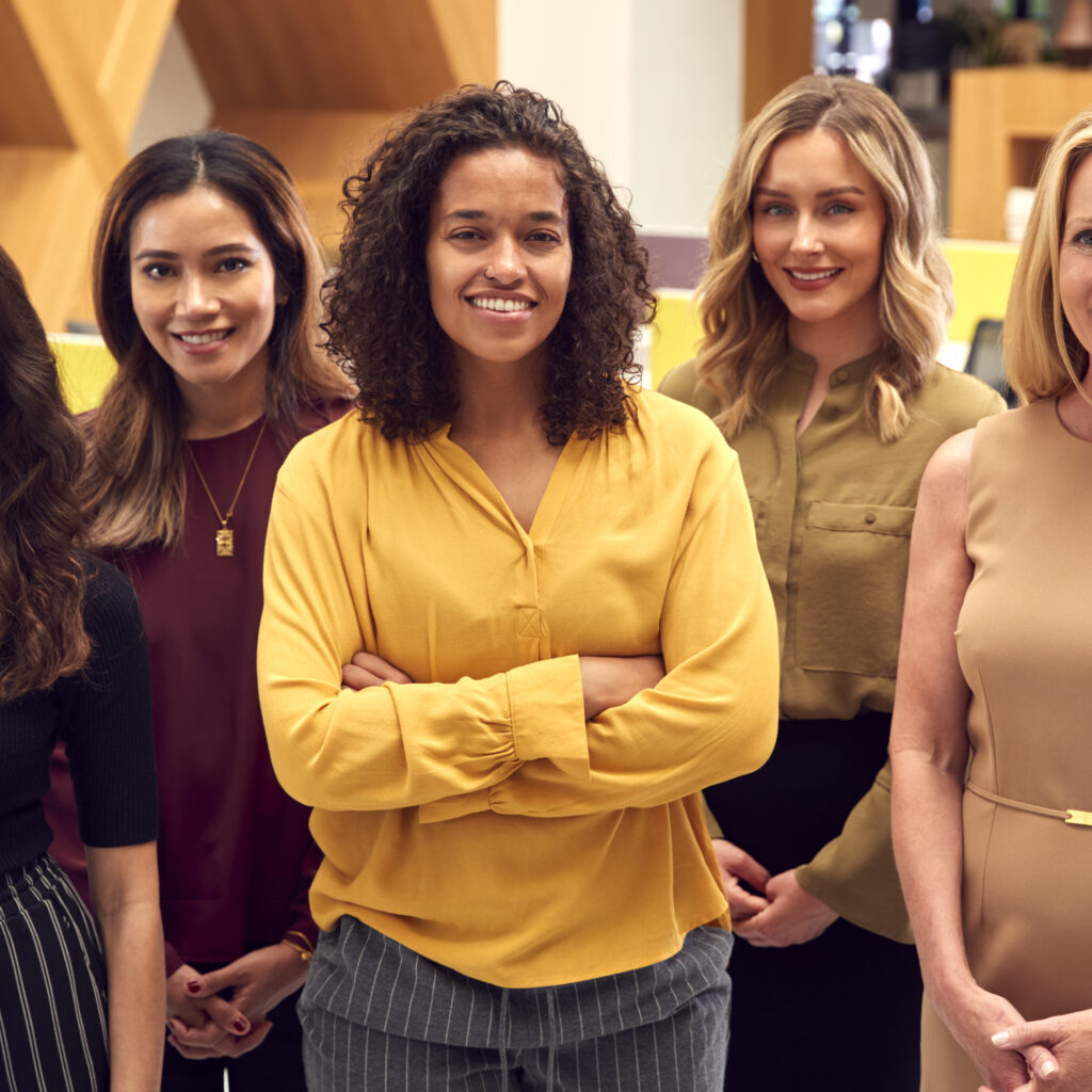 Portrait Of Multi-Cultural Female Business Team Standing In Modern Open Plan Office