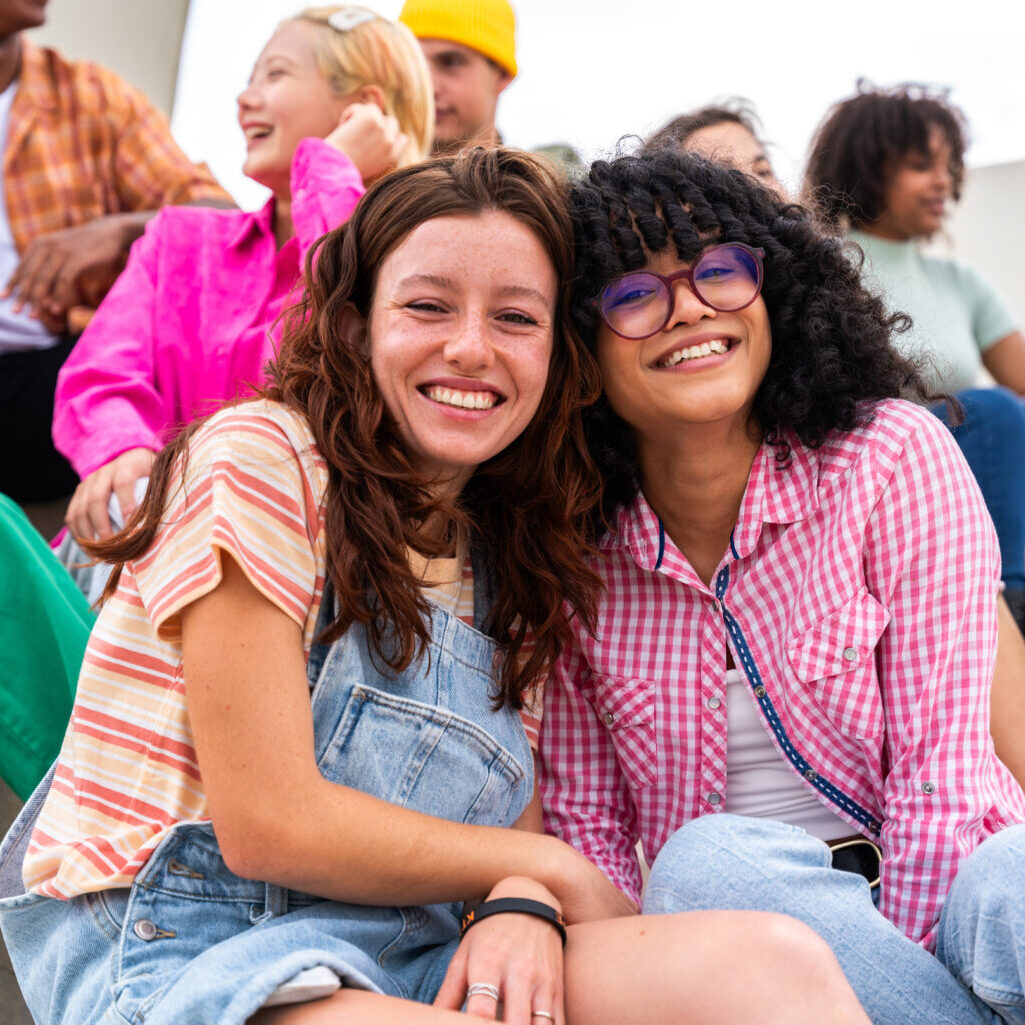 Happy playful multiethnic group of young friends bonding outdoors - Multiracial millennials students meeting in the city, concepts of youth, people lifestyle, diversity, teenage and urban life